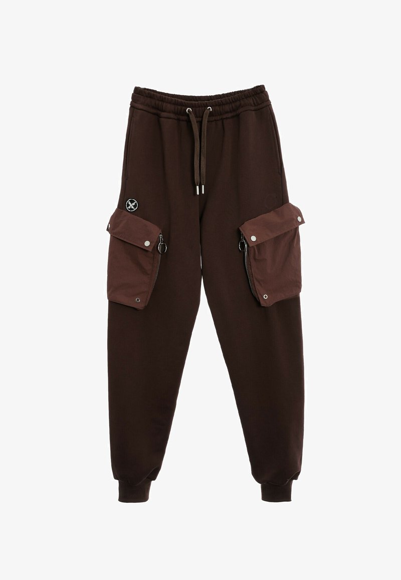 Pantalones de chándal marrones en un ajuste relajado con una cinturilla elástica, cierre de cordón y dos grandes bolsillos laterales con cremallera.