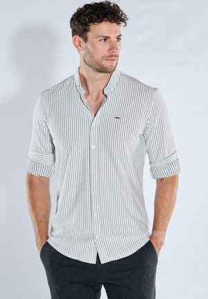 Weißes und graues gestreiftes Hemd mit Knopfleiste am Kragen, aufgerollten Ärmeln und kleinem Logo auf der Brust. Schlanke Passform.