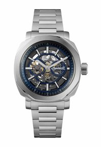 Klocka i rostfritt stål med skeletturverk, blå detaljer och borstad yta. Har ett armband av silvermetall och synliga rörelsekomponenter.