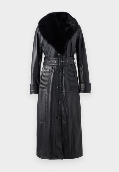 Μαύρο δερμάτινο παλτό με μακρύ σιλούετ, που διαθέτει ψεύτικη γούνα στον γιακά, λεπτομέρεια ζώνης και κάθετες ραβδώσεις στις τσέπες και τα μανίκια.