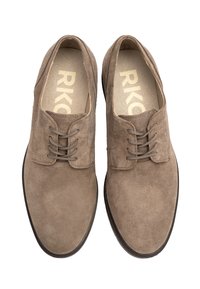 Zapatos de ante marrón con cordones y punta redonda, superficie texturizada y suela de goma oscura contrastante. Presenta un sencillo detalle de ojetes.