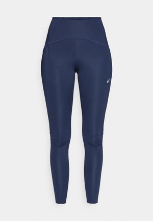 Navy blue high-waisted leggings with a smooth texture, featuring flat seams, side pockets, and a logo on the lower leg.