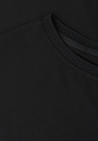 Tissu noir avec un gros plan d'un col arrondi présentant des côtes texturées et un détail de bande intérieure lisse.