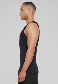 Fekete ujjatlan tank top bordázott anyagból, testhezálló kialakítással és kerek nyakkivágással, oldalról bemutatva egy modellen.