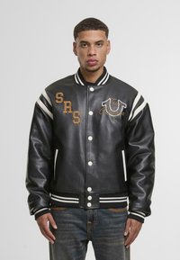 Juoda odinė universiteto striukė su baltais dryžiais, snapeliais, priekinėmis kišenėmis ir siuvinėjimais, įskaitant "SRS" ir "True Religion."