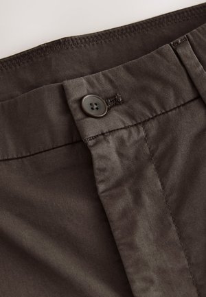 Ciemnobrązowa bawełniana tkanina z zapięciem na guziki i przeszyciami. Materiał ma gładką teksturę i subtelny połysk.