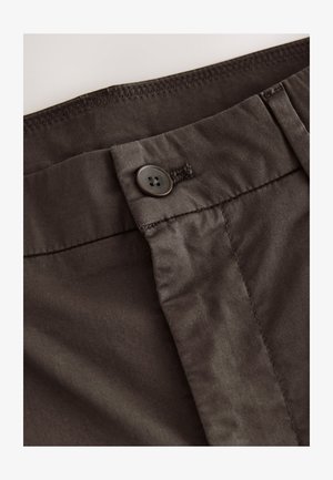 Ciemnobrązowa bawełniana tkanina z zapięciem na guziki i przeszyciami. Materiał ma gładką teksturę i subtelny połysk.