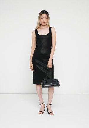 Zwarte midi-jurk met een vierkante halslijn en geribbelde textuur. Gecombineerd met een kleine zwarte handtas en stijlvolle sandalen met hoge hakken.