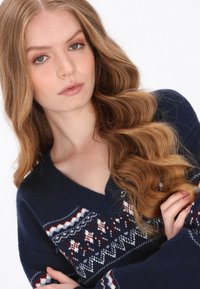 Pulover tricotat de culoare bleu marin, cu decolteu în V, având un motiv pe umeri în nuanțe de alb, roșu și albastru. Textură moale și mâneci lungi.