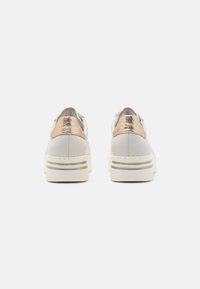 Sneaker bianche con un accento oro metallico sul tallone e strisce argento sulla suola; texture liscia e forma arrotondata.