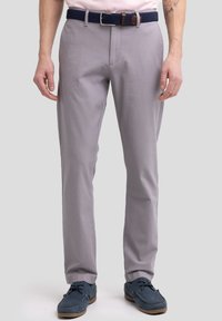 Pantalones ajustados gris claro con una textura suave, parte delantera plana y bolsillos laterales, combinados con un cinturón trenzado azul marino, usados con zapatos de barco azules.