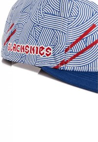 Gorra con visera azul, que presenta una tela blanca cubierta de patrones abstractos en azul y rojo, y texto bordado en rojo en el lado.