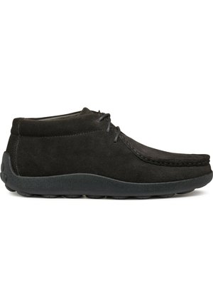 Botines de ante negro con puntera redondeada, detalles de costura y suela de goma negra, diseñados para ofrecer comodidad y un uso casual.