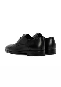 Chaussures habillées en cuir noir avec une finition lisse, un bout arrondi et des détails de couture minimaux ; lacées avec un talon empilé bas.
