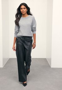 Light gray knit sweater with crew neckline worn with black faux leather wide-leg pants. Black pointed-toe heels complete the outfit.