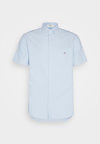 Svetlomodrá košeľa s krátkym rukávom na gombíky, golierom na gombíky a malou vreckom na ľavej strane hrude s detailom loga.