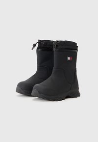 Botas negras impermeables con parte superior suave, parte superior elástica, suela texturizada y un pequeño parche con logo. Cuenta con un regulador para un ajuste ajustable.