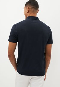 Marinefarbenes Poloshirt, kurze Ärmel, lässige Passform, weiches Baumwollmaterial. Verfügt über einen klassischen Kragen und ein einfaches Design ohne Muster oder Akzente.