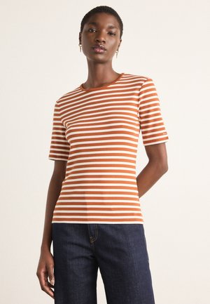 Stripet t-skjorte med horisontale oransje og hvite striper, rund hals, korte ermer og en tettsittende design, parret med mørk denimjeans.