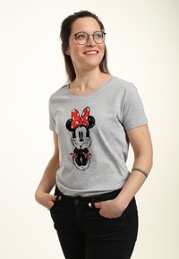 Szara bawełniana koszulka z grafiką Myszy Miki, z czerwoną kokardą w kropki. Krótkie rękawy i okrągły dekolt. Czarne spodnie.