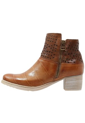 Bottine marron en cuir avec une tige texturée ornée de motifs découpés, une fermeture éclair latérale et un talon bloc avec une semelle de couleur claire.