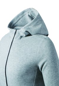 Grå zip-up hoodie med huva, tillverkad av mjukt tyg. Har en kontrasterande svart dragkedja och subtil struktur. Inga synliga logotyper eller mönster.