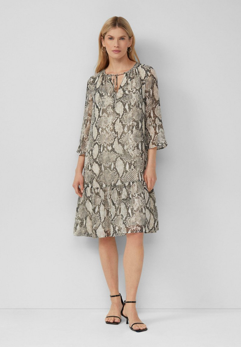 Leichtes Kleid im Schlangendruck-Muster, mit einem Schlüsselaugenhals, Dreiviertelärmel und einem ausgestellten Saum. Farbschema: beige und braun.