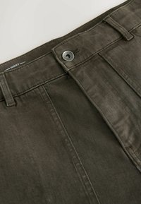 Dunkelgrüne Denim-Hosen mit glatter Textur, ausgestattet mit einem Metallknopf an der Taille und flachen Fronttaschen. Nähte sind sichtbar.