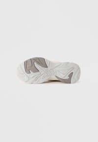 Schuhsohle mit strukturiertem Design, bestehend aus einer Mischung aus durchscheinendem Weiß und grauem Gummi. Gebogene Muster verbessern den Grip.