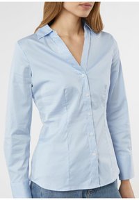 Light blue striped button-up shirt with a pointed collar, long sleeves, fitted design, soft texture, and white buttons.