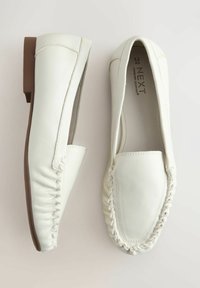 Balti odiniai bateliai be kulno, apvaliu priekiu, siuvinėtomis detalėmis kraštuose ir žemu rudu guminiu padu. Sukurti patogumui.