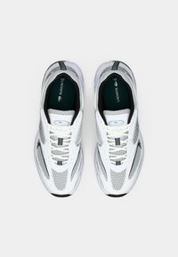 White athletic shoes with a mesh upper, grey accents, and a cushioned sole. Features laces and a Lacoste logo on the tongue.