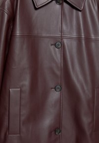 Giacca di pelle borgogna con una texture liscia, grande colletto e sei bottoni neri. Include due tasche laterali e dettagli cuciti.