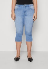 Lyseblå, cropped jeans med en skreddersydd passform, som har frontlommer og en subtil falmet design, sammen med svarte ballerinasko.