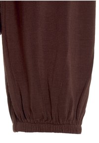 Brauner, strukturierten Stoff mit einem elastischen Bündchen am unteren Ende. Der Stoff wirkt leicht und leicht zerknittert, was auf eine lockere Passform hinweist.