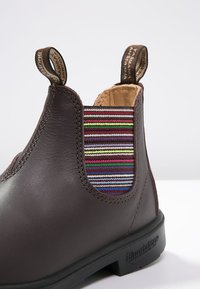 Hnědé kožené kotníkové boty s barevnou pruhovanou elastickou vsadkou, kulatou špičkou, pevnou podrážkou a poutky pro snadné obouvání.