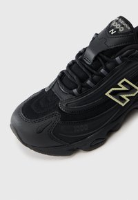 Μαύρο sneaker με επάνω μέρος από μαesh, καουτσούκ σόλα και υφή επικαλύψεις. Εμφανίζει επωνυμία στη γλώσσα και στο πλάι με μοναδικό σχέδιο.