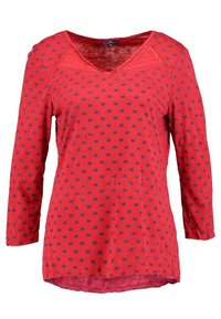 Top lungo rosso a maniche lunghe con scollatura a V, caratterizzato da un motivo di piccole forme blu. Materiale morbido con vestibilità rilassata e orlo arrotondato.