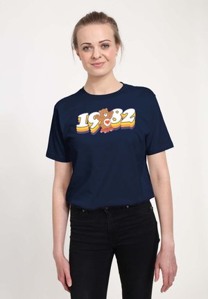 Granatowa koszulka z krótkim rękawem z graficznym wzorem przedstawiającym kolorowe "1982" oraz misia na rolkach. Wykonana z miękkiej bawełny, luźny krój.