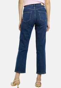 Tumehallid kõrge vöökohaga teksad sirgete sääredega, nähtavate tagataskutega ja puhta äärisega. Valmistatud denimkangast, millel on tekstuuriga pind.