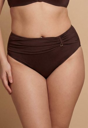 Kobieta nosząca ciemnobrązowe bikini z wysokim stanem, z marszczonym detalem materiału i pierścieniowym akcentem po lewej stronie na beżowym tle.