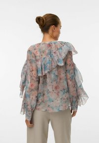 Blusa floreale in tessuto trasparente, con motivi rosa e blu, dettagli arricciati lungo le spalle e le maniche, e scollatura rotonda.