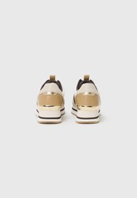 Scarpe da ginnastica oro e beige con un'accattivante finitura dorata sul tallone, dotate di suole a strisce nere e bianche. Materiali in pelle liscia e rete.