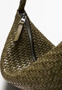 Sac en cuir vert olive tissé de forme incurvée, avec une fermeture éclair en argent et une surface texturée, mettant en valeur des motifs de tissage complexes.