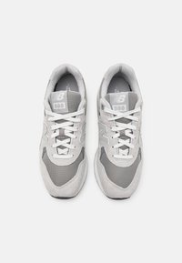 Világosszürke tornacipők, amelyek nubuk és hálós anyag kombinációjából készültek, fehér fűzőkkel, párnázott bokarazettel és logó részletekkel a nyelvén.