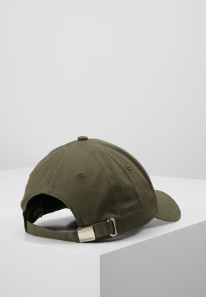 Olivengrøn justerbar baseballkasket med metal spænde og Calvin Klein logo på den bageste rem, placeret på en hvid overflade.