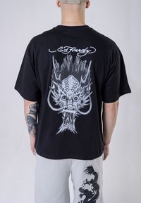 Black cotton t-shirt featuring a large silver dragon graphic on the back, with the text "Ed Hardy" above. Relaxed fit and short sleeves.