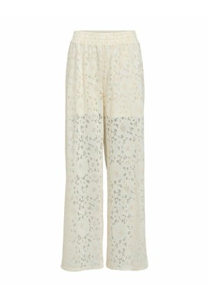 Pantalon large couleur crème avec motif en dentelle florale et taille élastique, semi-transparent à partir du milieu de la cuisse vers le bas.