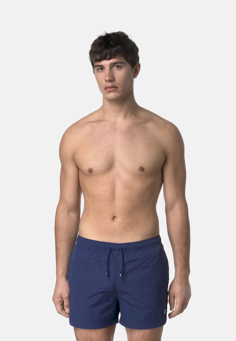 Pantaloni da bagno blu navy in tessuto texturizzato, con vita elasticizzata e cordoncino. Il modello è in piedi con un'espressione neutra e il torso nudo.