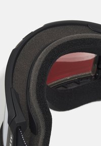 Skibril met een zwart frame, zachte schuimvoering en een reflecterende lens met een rode tint, ontworpen voor comfort en bescherming.